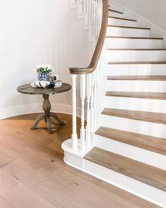 there is a small table with flowers on it next to the stairs in this house