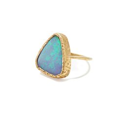 a gold ring with an opal stone in the center, on a white background