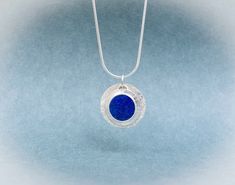 This sterling silver 'coin' pendant features a round, flat Lapis Lazuli Gemstone that is an amazing even shade of celestial blue.  We styled this pendant with two sterling silver discs - the back one is textured and is .80 inches round. The disc with the Lapis Lazuli is a bit larger than one half inch. This modern, playful, Lapis Lazuli necklace is on an Italian-made sterling silver snake chain with lobster clasp. At checkout, you have a choice of a 16 or 18 inch length. A great gift for Lapis l Cabin Studio, Celestial Blue, Lapis Lazuli Pendant, Lapis Lazuli Necklace, Lapis Lazuli Gemstone, Silver Snake Chain, Disc Pendant, Silver Coin, Pendant Silver