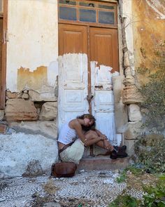 a woman sitting in front of an old door