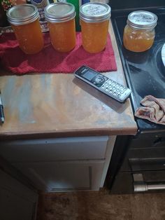 jars of honey sit on top of a stove next to a cell phone and food