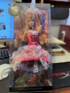 a barbie doll in a pink dress on a desk