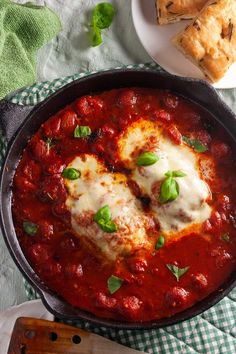 a skillet filled with sauce and cheese on top of a table