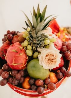 a bowl filled with fruit and flowers on top of a table