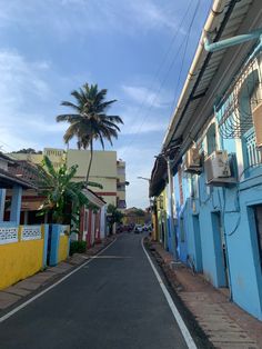 an empty street lined with colorful buildings and palm trees