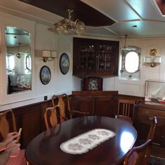 a dining room table and chairs in front of a cabinet with two mirrors on the wall