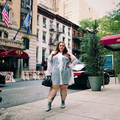 a woman is standing on the sidewalk in front of buildings