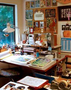 a cluttered desk with lots of art on the wall