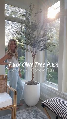 a woman standing in front of a window next to a potted tree