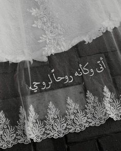 an arabic writing on the side of a white dress with lace and sequins