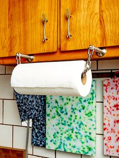 a roll of toilet paper is hanging on the kitchen wall next to some colorful napkins