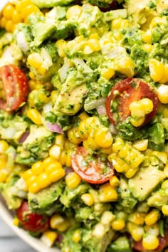 corn salad with avocado and tomatoes in a white bowl