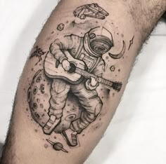 an astronaut tattoo on the leg of a man with a guitar and space shuttle in his hand