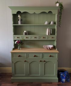 an old green china cabinet with flowers on top