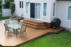 a backyard deck with chairs and table in the grass