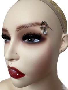 a mannequin's head with fake eyelashes and piercings on the forehead