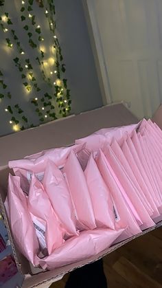 an open box filled with pink bags on top of a hard wood floor next to a christmas tree