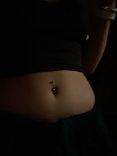 a woman's belly with piercings on it and a wine glass in her hand