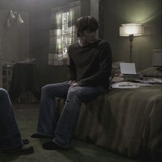 two young men sitting on top of a bed in a bedroom next to each other