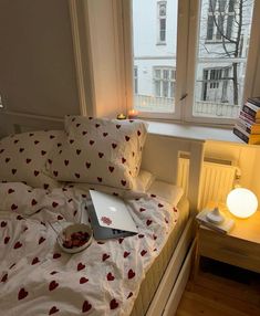 a laptop computer sitting on top of a bed next to a window with hearts on it