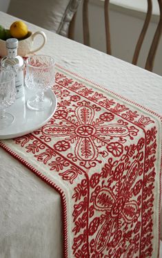 a white table topped with a red and white table cloth next to a bowl of fruit