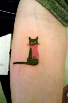 a black cat with a pink shirt on it's leg is shown in this tattoo