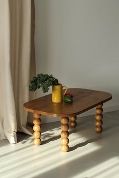 a wooden table with a potted plant sitting on it's top next to a window