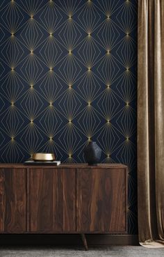 a sideboard with a vase on it in front of a wallpapered background