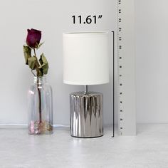 a vase with a rose next to a measuring ruler