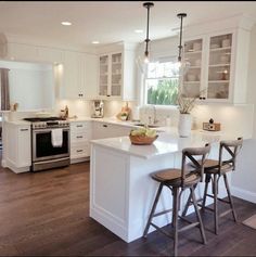 a kitchen with white cabinets and wooden floors