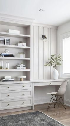 a white desk sitting next to a window in a room with bookshelves and shelves