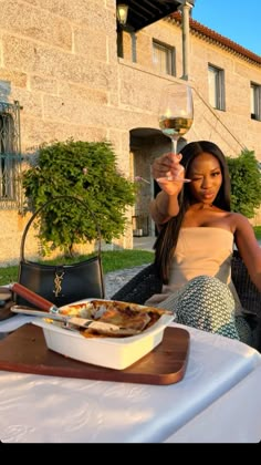 a woman sitting at a table with a glass of wine in front of an old building