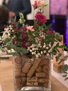 a vase filled with lots of flowers and wine corks on top of a table