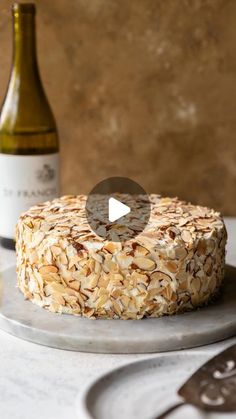 a cake on a plate next to a bottle of wine