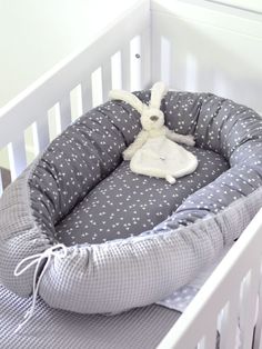 a baby crib with a stuffed animal in it's bed on the floor