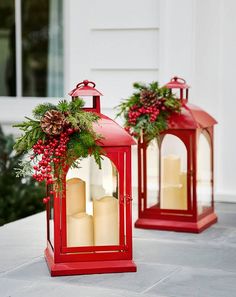 two red lanterns decorated with holly and pine cones