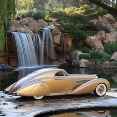 an antique car parked in front of a waterfall