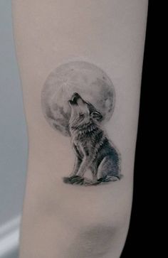 a black and white tattoo of a wolf sitting on the ground under a full moon