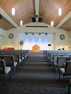 an empty church with rows of chairs facing the alter and stage lights in the background