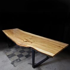 a wooden table sitting on top of a checkered floor in front of a black wall