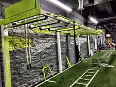 an indoor gym with artificial turf and ladders