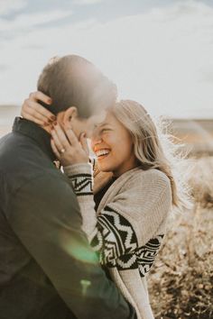 a man and woman standing next to each other in front of the sun with their faces close together