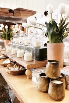 a table topped with lots of vases filled with white tulips and other flowers