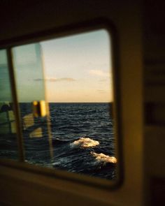 the reflection of an ocean wave seen through a boat's side window at sunset