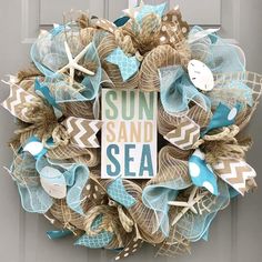 a wreath that says sun sand sea on the front door with starfishs and seashells