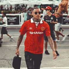 a man in a red shirt is walking down the street with other people behind him