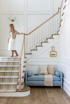 a woman standing on top of a stair case next to a blue couch