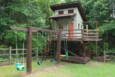 a wooden swing set in front of a tree house