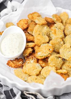 a white plate topped with fried food next to a bowl of ranch dressing