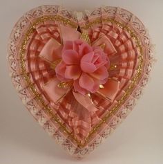 a heart shaped box with a pink flower in the center and lace trim around it